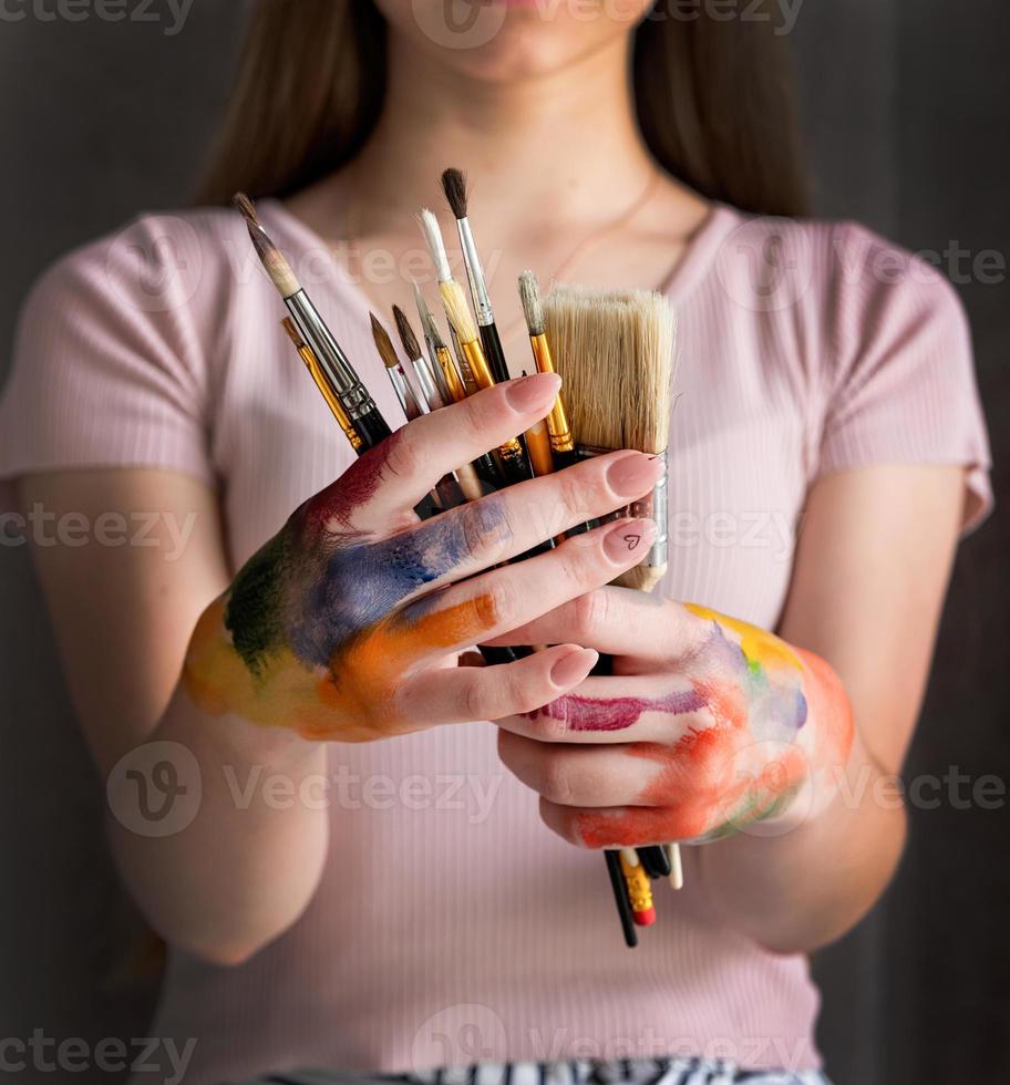 mani dell'artista femminile che tengono i pennelli foto