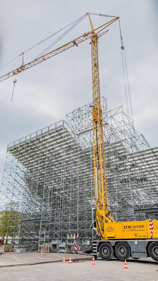 giallo mobile gru a un' costruzione luogo con impalcatura, Parigi, Francia, aprile 14, 2024, raffigurante urbano sviluppo e ingegneria foto