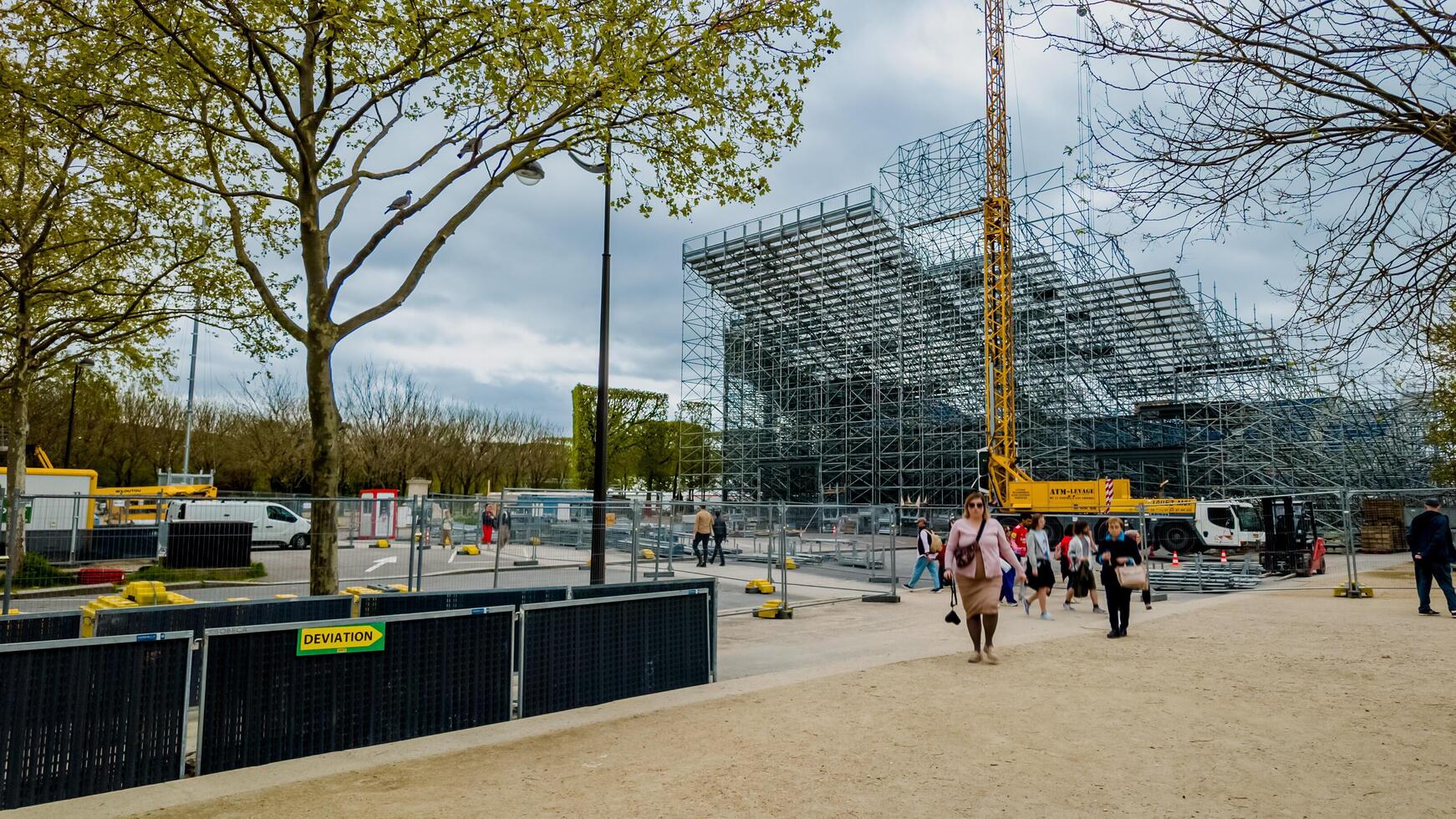 visitatori a piedi di il in corso costruzione di un' moderno struttura nel Parigi, Francia, sotto primavera fioritura su aprile 14, 2024, riflettendo urbano sviluppo e turismo foto