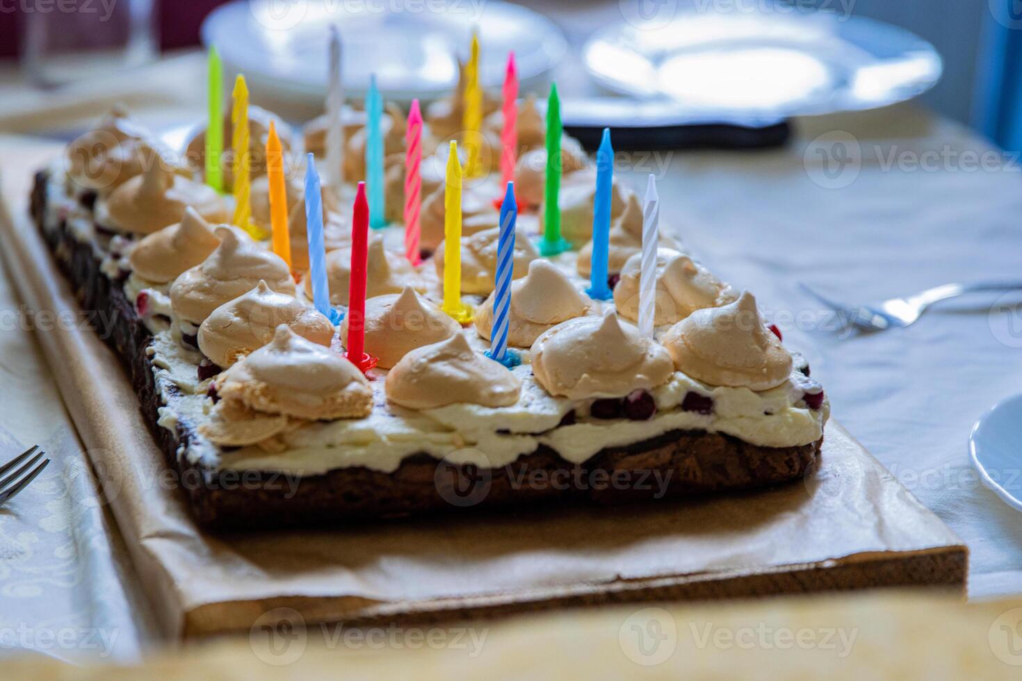 bellissimo compleanno torta con bianca frustato crema, meringhe e mirtilli, decorato con multicolore candele. contento compleanno concetto. modello per carta, manifesto, striscione. lato Visualizza. selettivo messa a fuoco foto