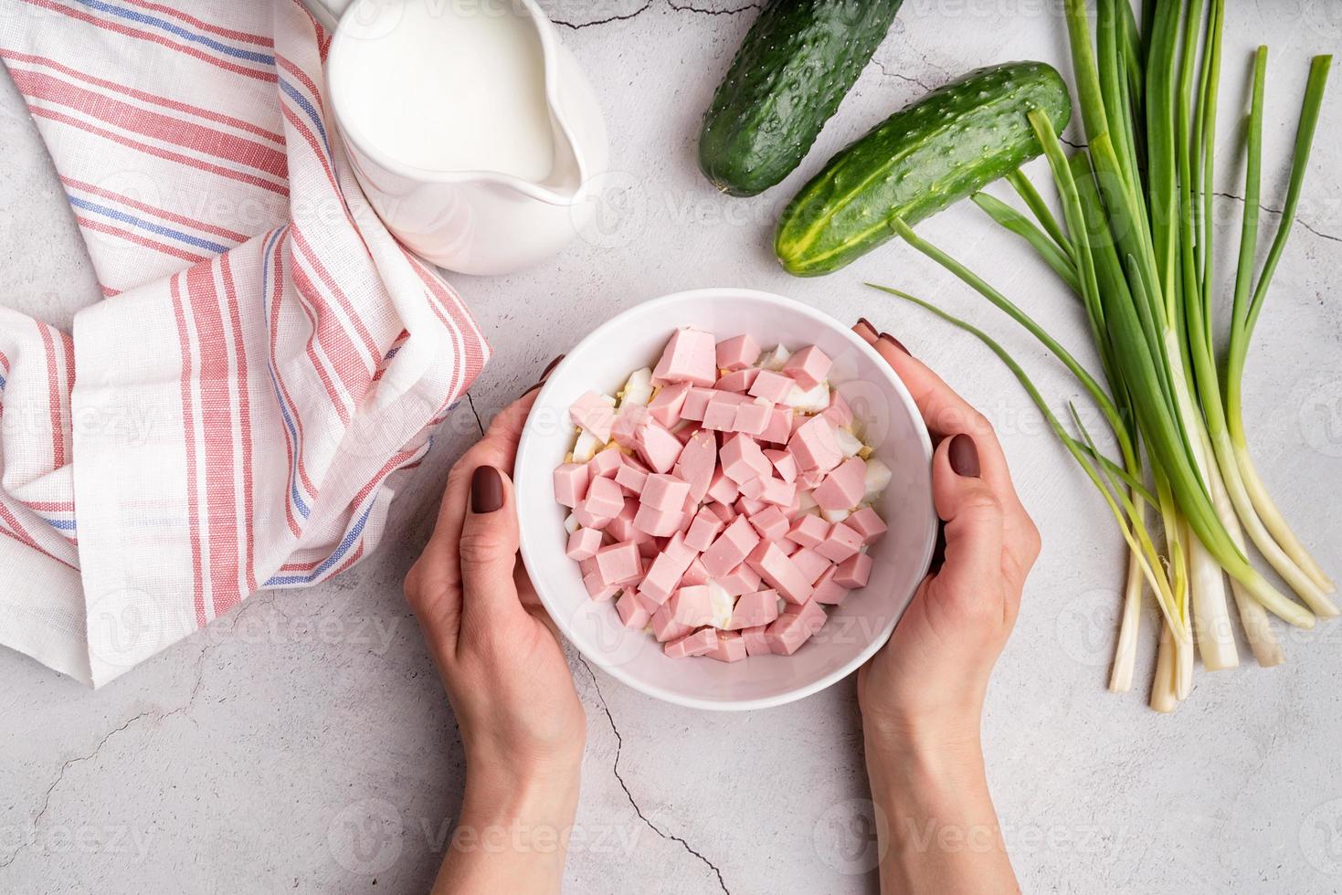 preparazione passo passo della zuppa fredda di okroshka con salsiccia, passaggio 4- aggiunta di salsicce affettate alla ciotola vista dall'alto foto