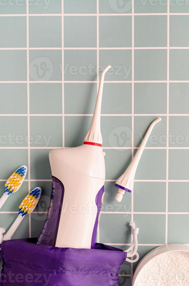 irrigatore della bocca, spazzolini da denti e vista dall'alto della polvere dentale su sfondo blu foto