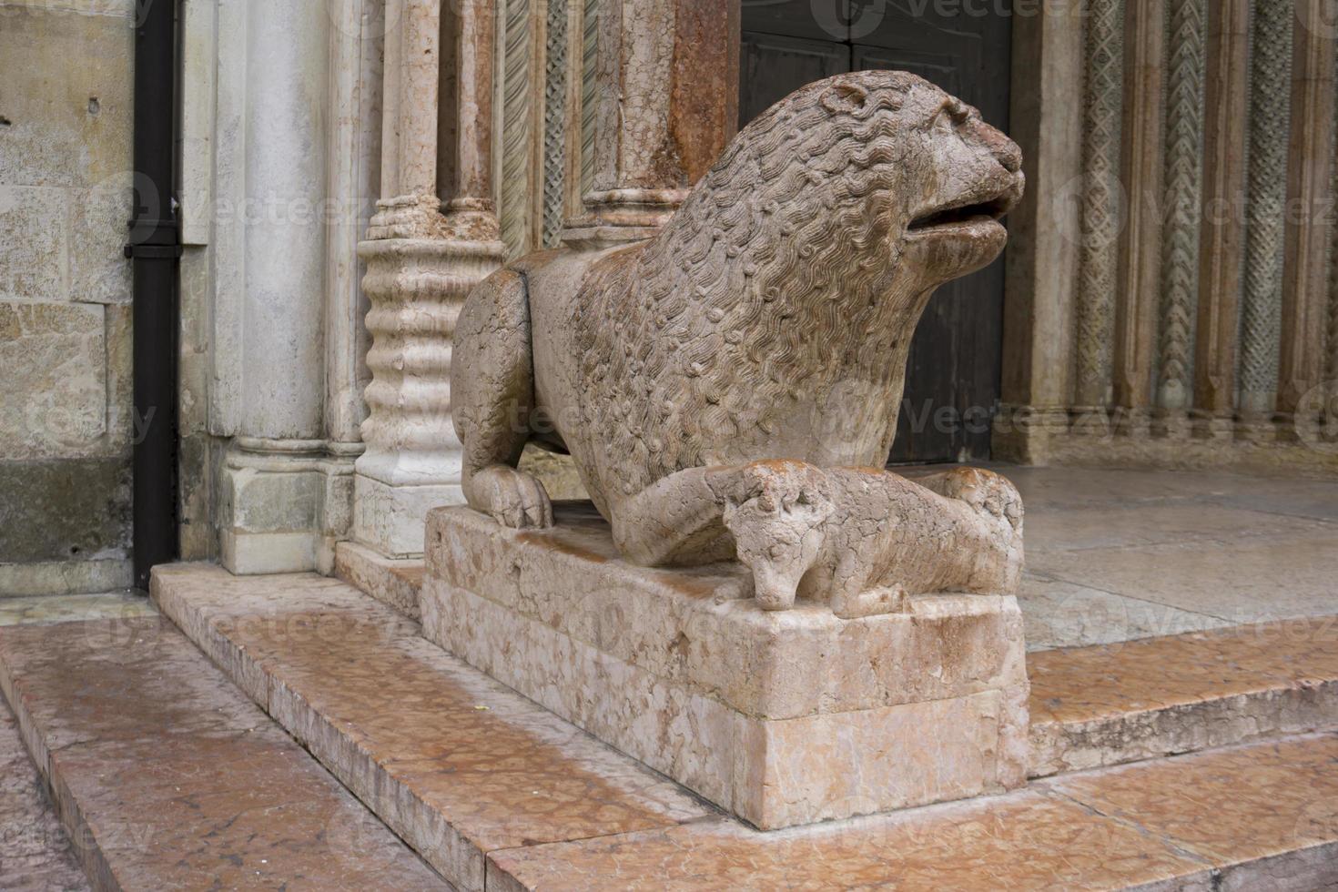 Scultura di leone con pregare davanti al duomo di modena, italia foto