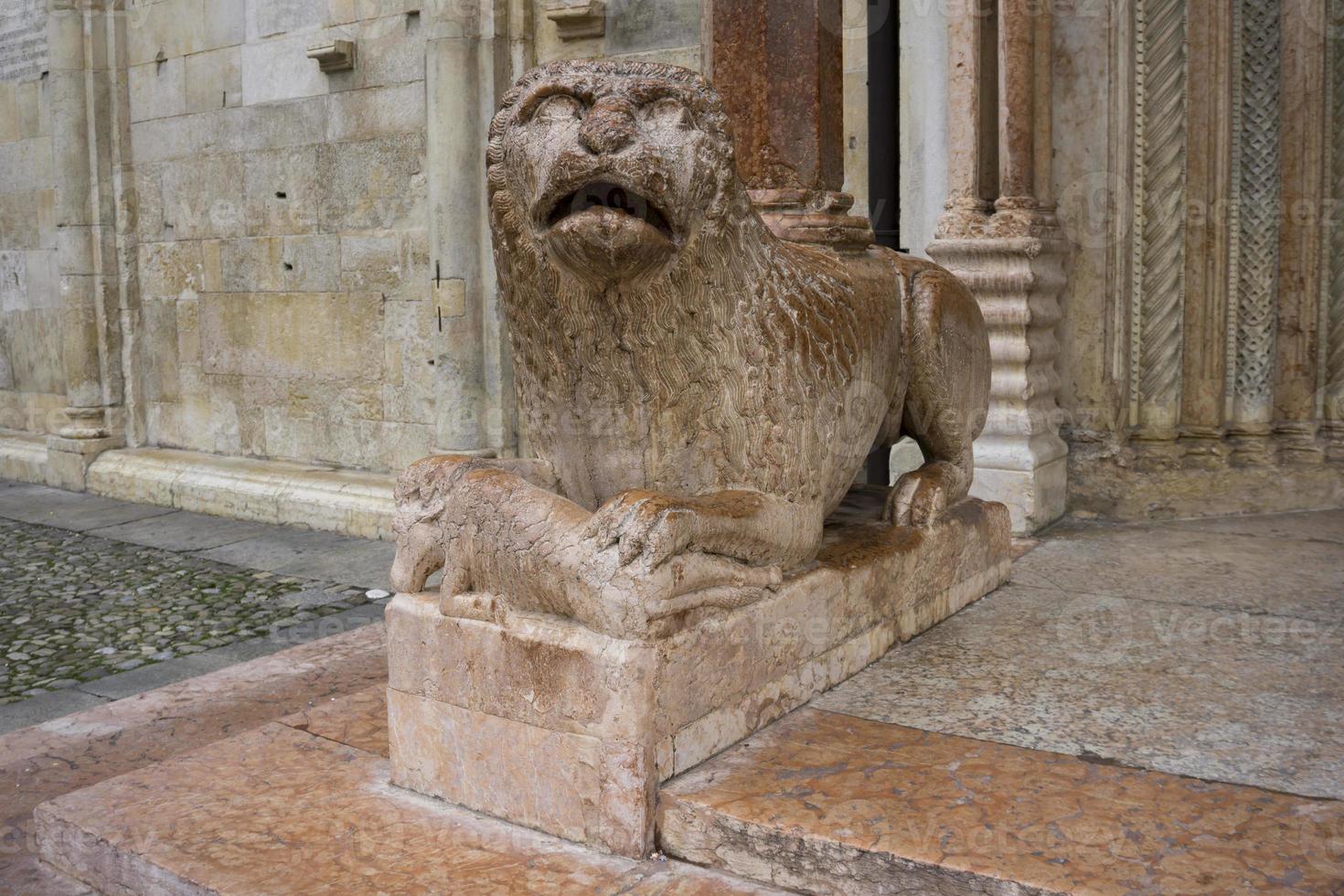 Scultura di leone con pregare davanti al duomo di modena, italia foto