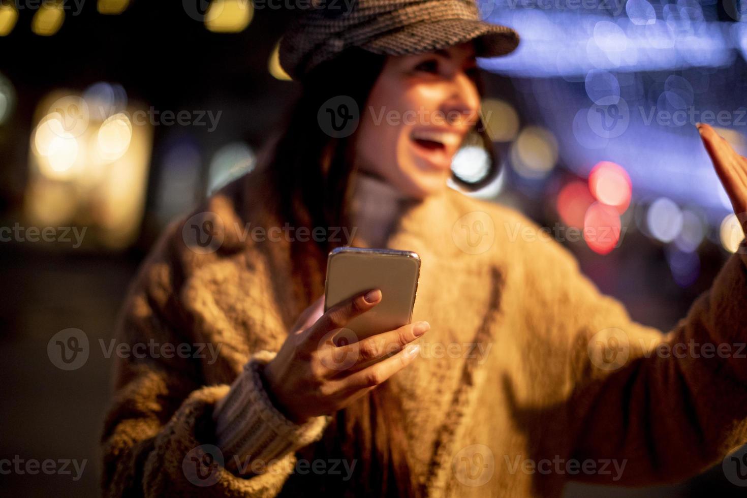 bella giovane donna che usa il suo telefono cellulare in strada a Natale foto