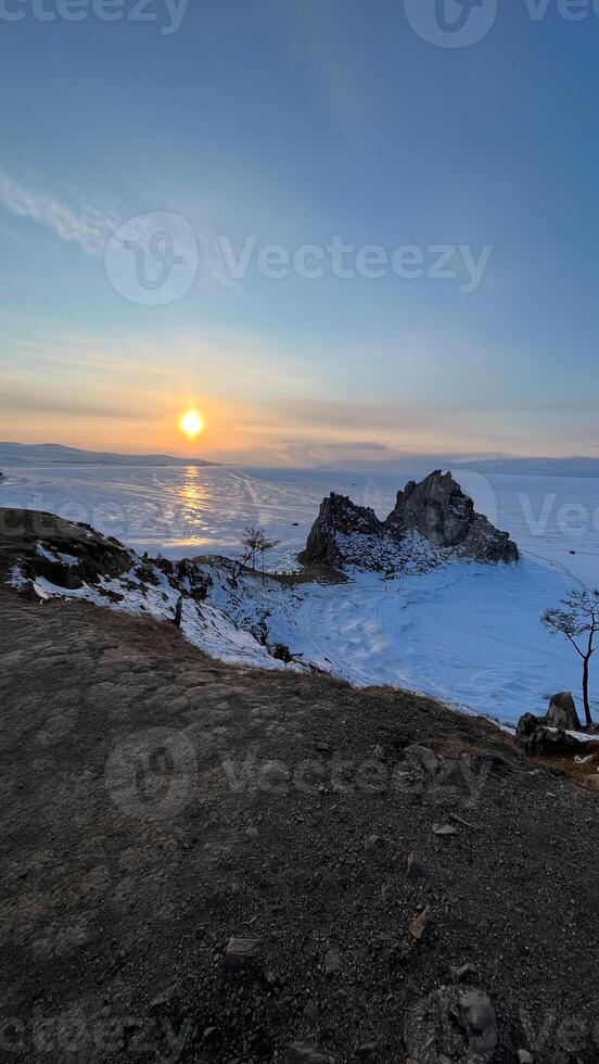 tramonto su il spiaggia di lago baikal con rocce nel davanti neve riva baikal inverno foto