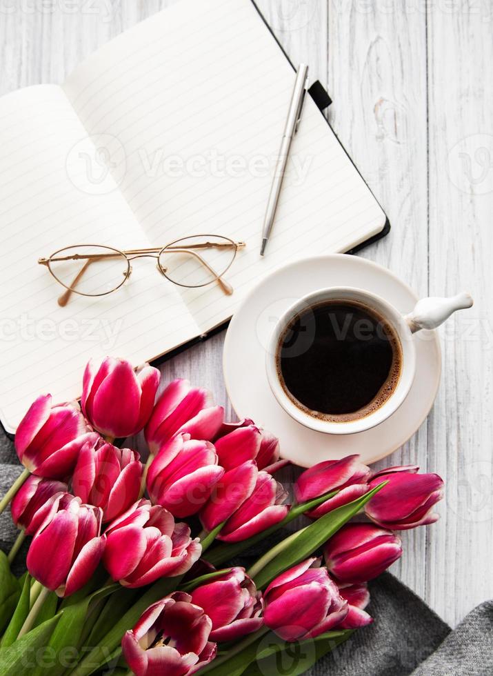 quaderno, tazza di caffè e tulipani rosa foto