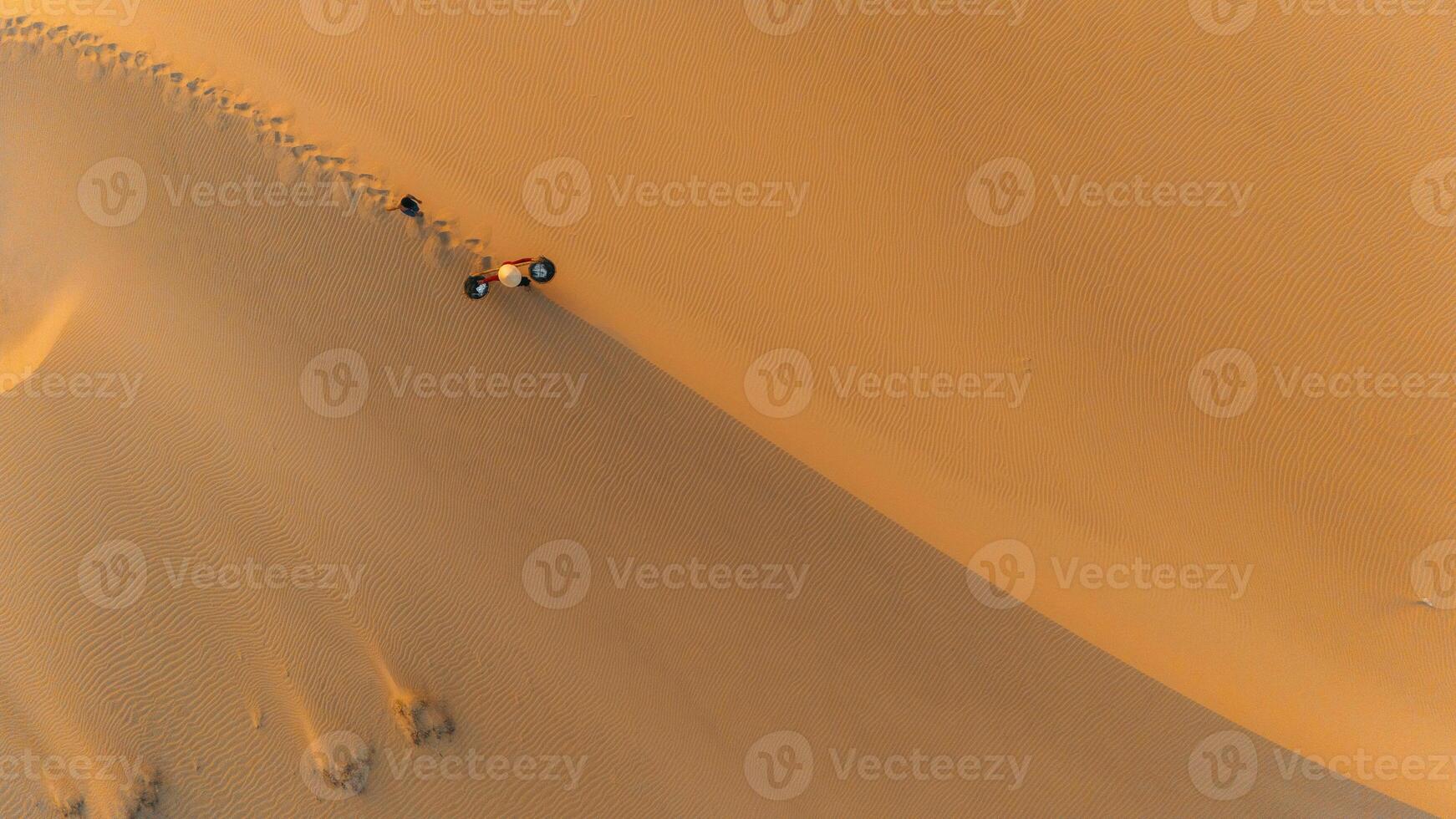 aereo Visualizza di un' contadino donna trasporta un' bambù telaio su il spalla attraverso sabbia dune nel ninh gio Provincia, Vietnam. esso è uno di il maggior parte bellissimo posti nel Vietnam foto