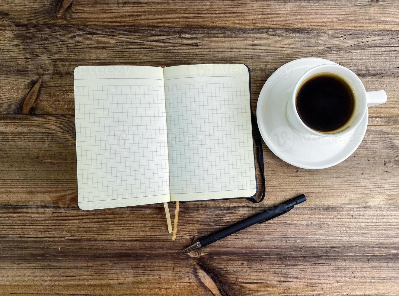 caffè nel un' tazza e un' taccuino con un' penna su il tavolo, superiore Visualizza. foto