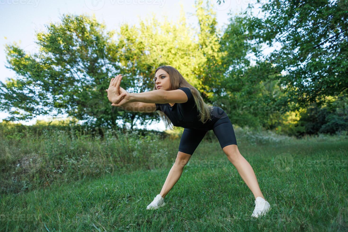 un' ragazza fare gli sport nel il parco esegue inoltrare curve. atletico ragazza nel un' stretto uniforme Lavorando all'aperto nel il parco. foto