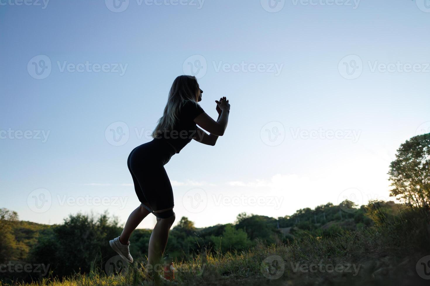 silhouette di un' ragazza contro il sfondo di tramonto ragazza fare gli sport. atletico ragazza nel un' stretto uniforme Lavorando all'aperto nel il parco. foto