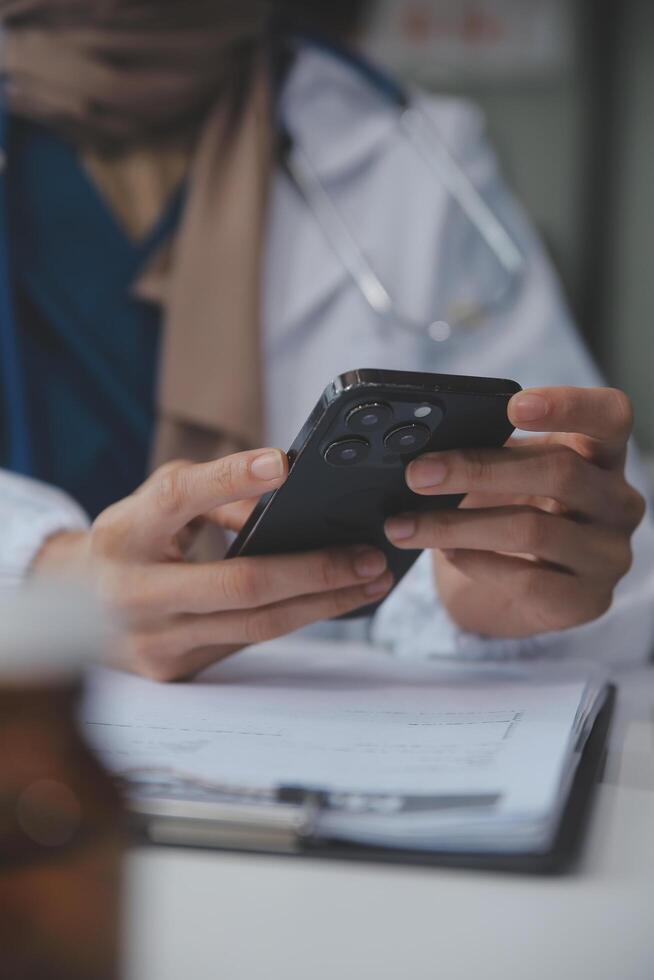 consultazione in linea. irriconoscibile medico utilizzando smartphone a posto di lavoro, messaggistica con paziente, prescrivere trattamento foto