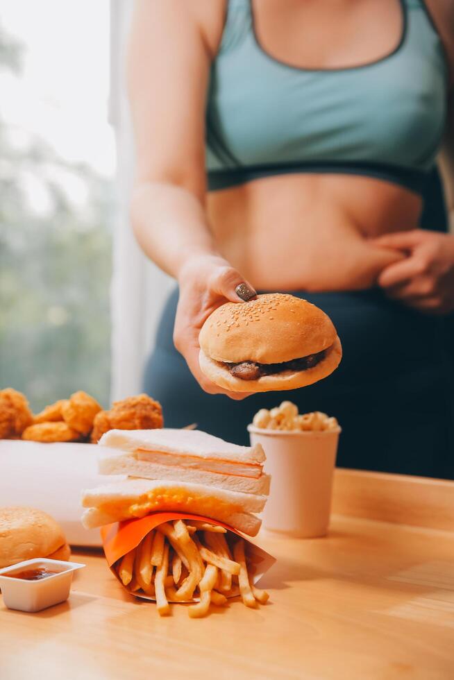 per mangiare o non. triste paffuto donna guardare a il hamburger mentre pensiero per mangiare esso o non foto