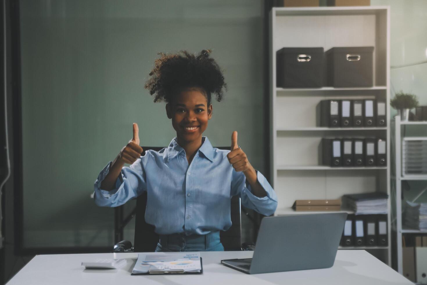 felice eccitata imprenditrice asiatica di successo che trionfa con uno smartphone per computer portatile nell'ufficio del posto di lavoro foto