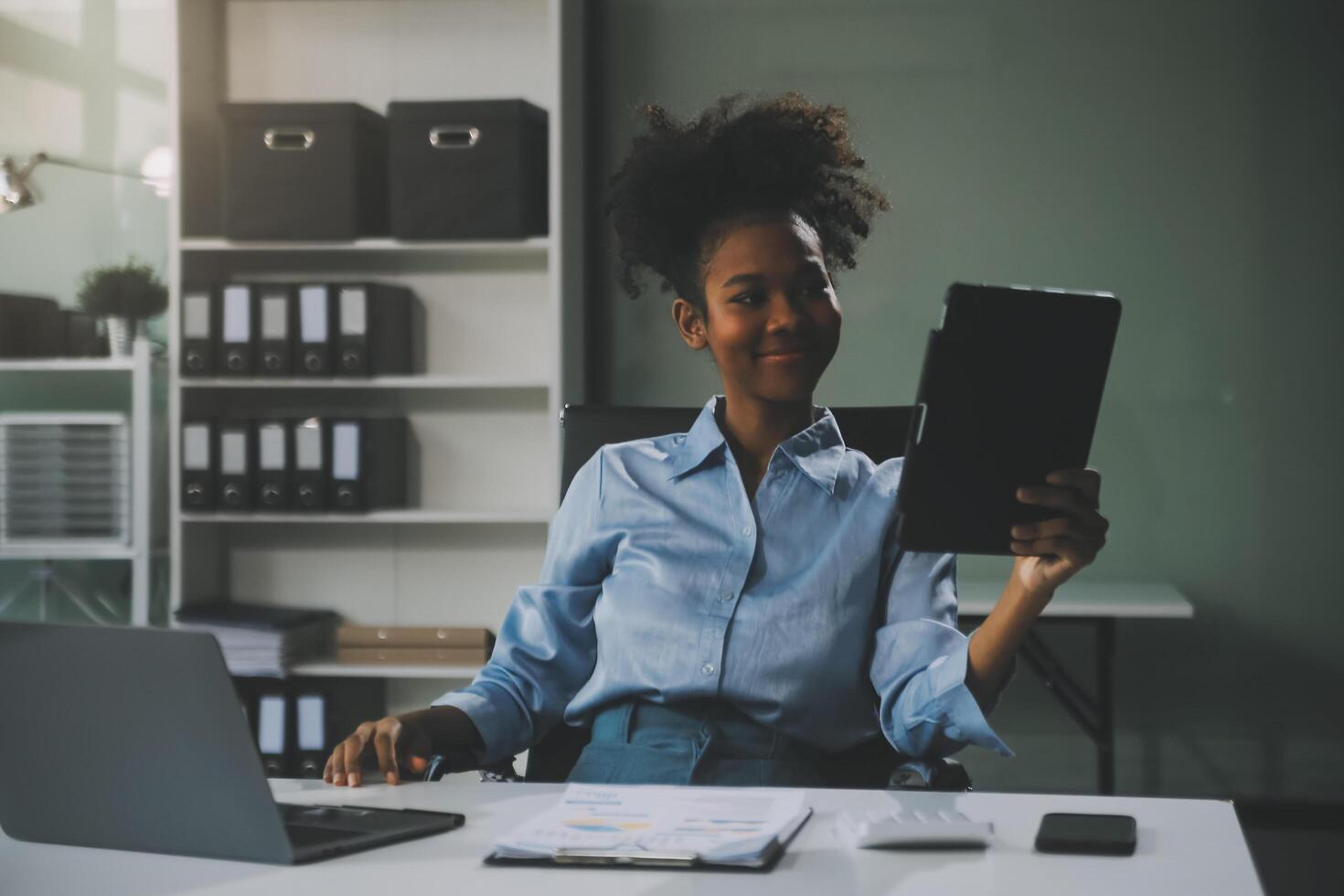 felice eccitata imprenditrice asiatica di successo che trionfa con uno smartphone per computer portatile nell'ufficio del posto di lavoro foto