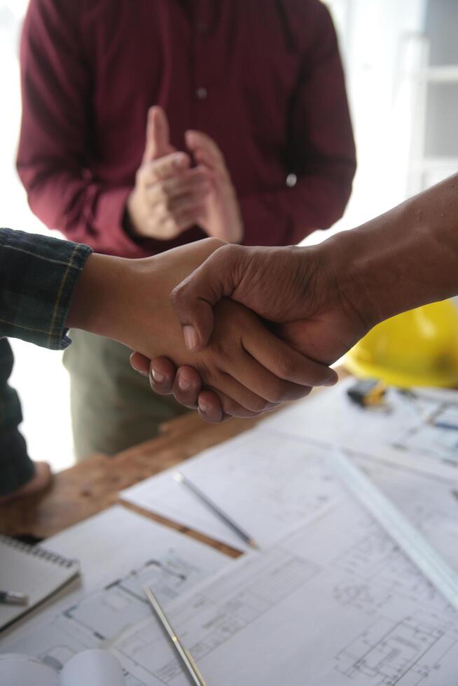 ingegnere e contraente aderire mani dopo firma contratto, loro siamo avendo un' moderno edificio progetto insieme. riuscito cooperazione squadra concetto foto