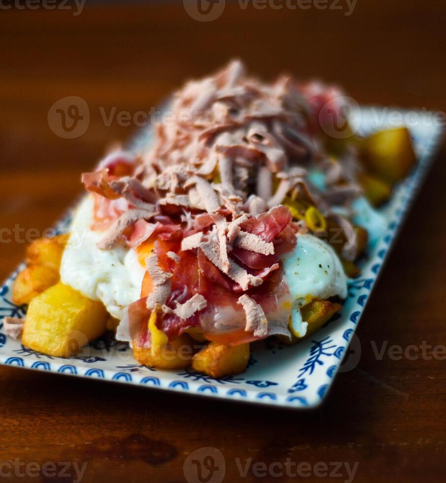 porzione di patate con fritte uova e guarito iberico prosciutto. foto