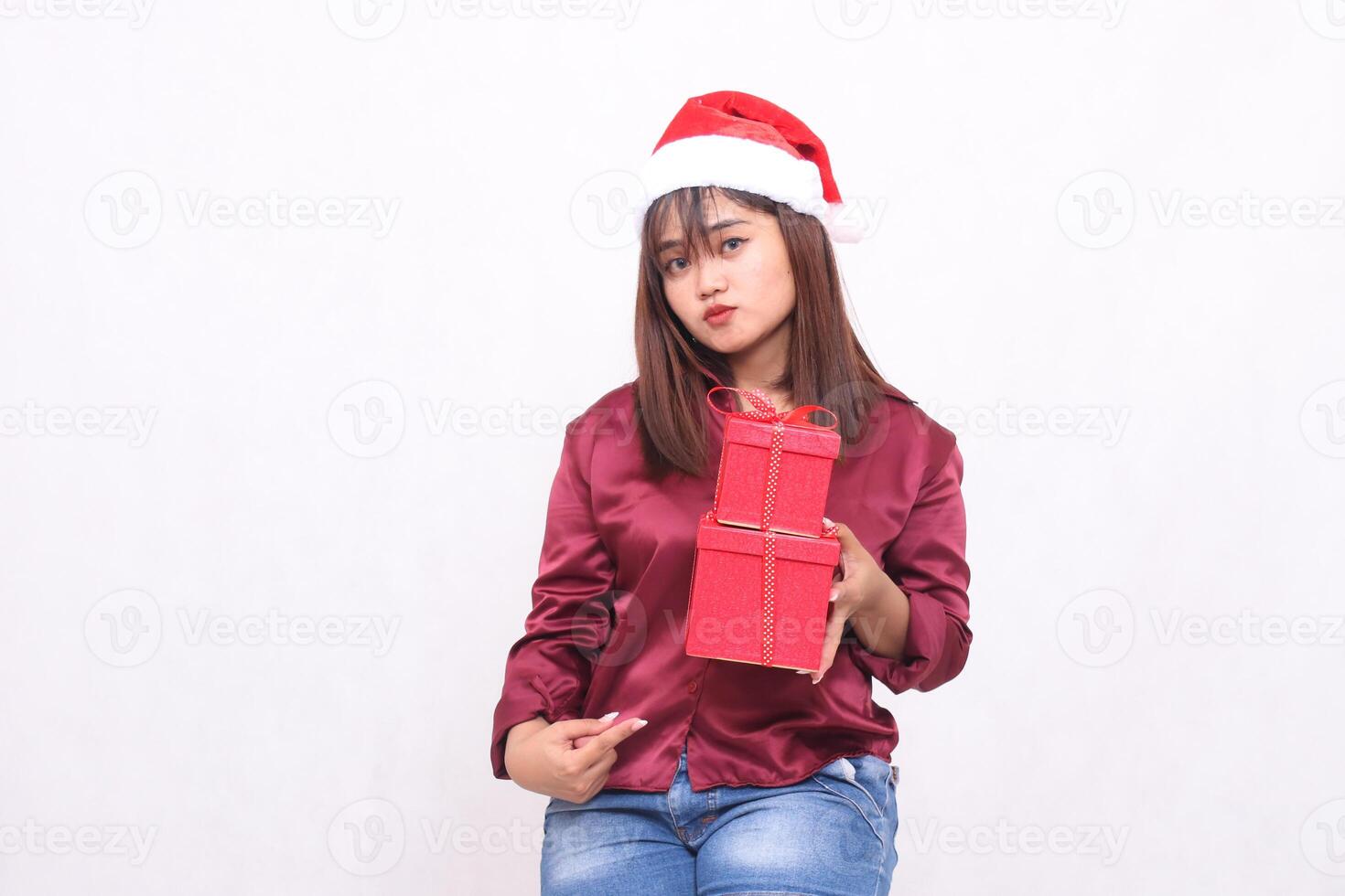 bellissimo giovane asiatico indonesiano ragazza imbronciato trasporto regalo scatola nel Natale Santa Claus cappello attrezzatura rosso camicia moderno appuntito parte inferiore scatola su bianca sfondo per promozione e pubblicità foto