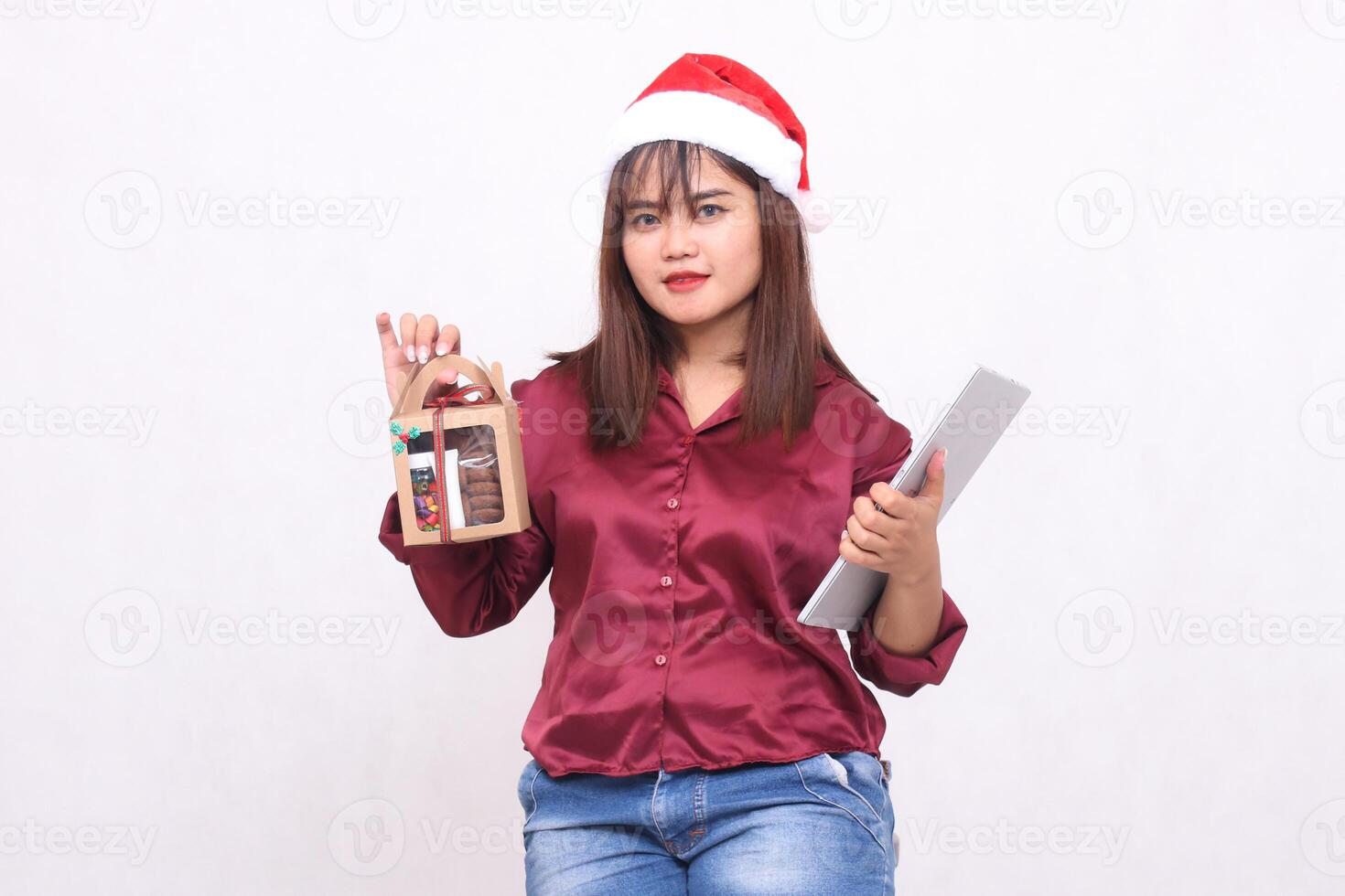 bellissimo giovane elegante sud-est asiatico donna portando cibo i regali nel ostacolare e il computer portatile tavoletta a Natale indossare Santa cappello moderno rosso camicia attrezzatura bianca sfondo per promozione e pubblicità foto