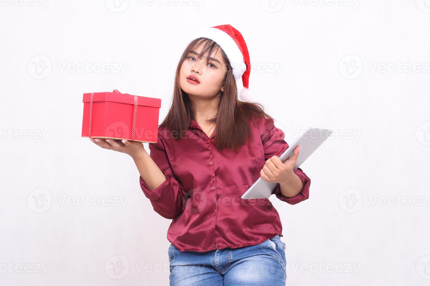 bellissimo giovane elegante sud-est asiatico donna portando regalo ostacolare e tavoletta il computer portatile a Natale indossare Santa cappello moderno rosso camicia attrezzatura bianca sfondo per promozione e pubblicità foto
