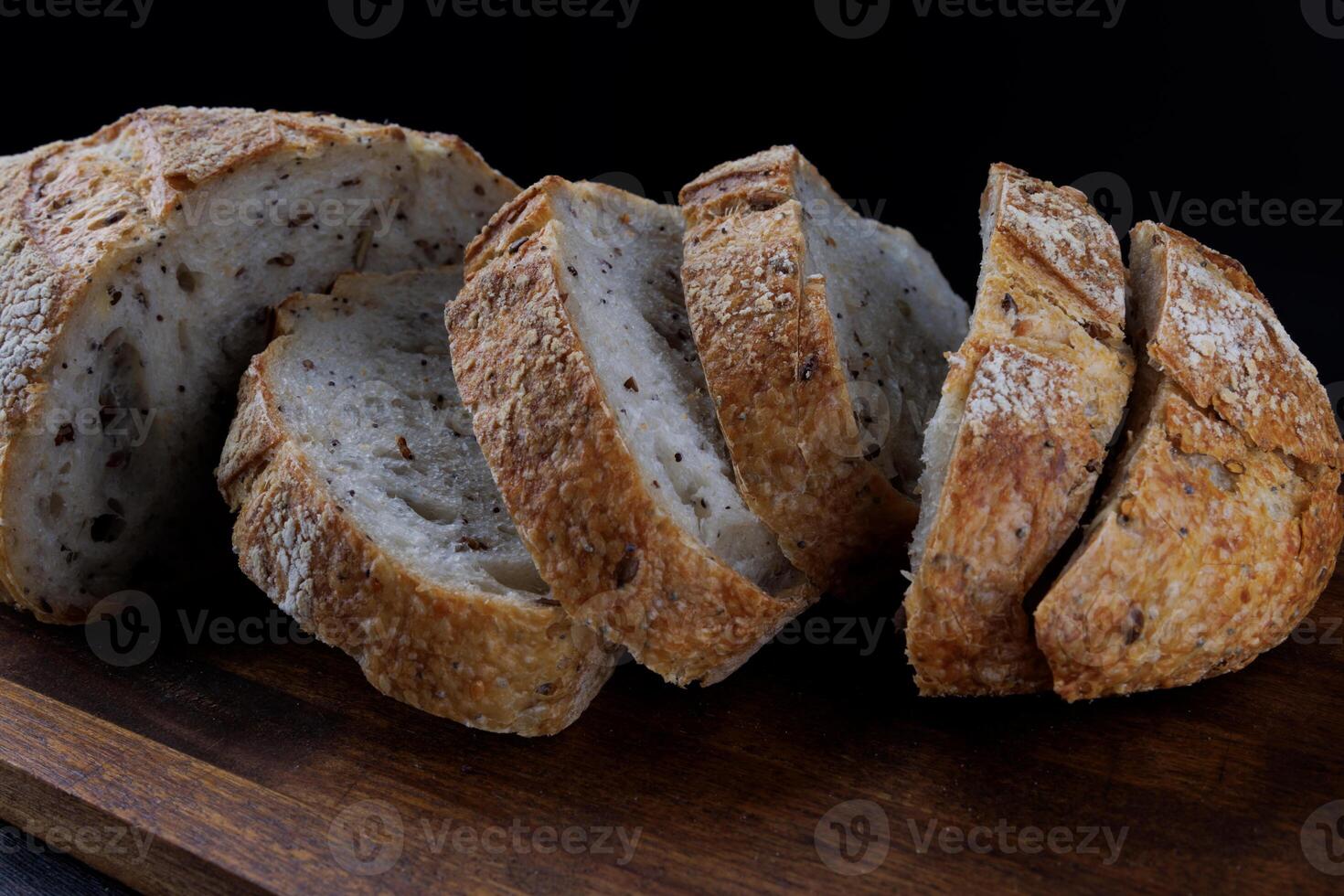 tagliare pagnotta con semi su un' di legno tavola. affettato pezzi di pane. arte pane. foto