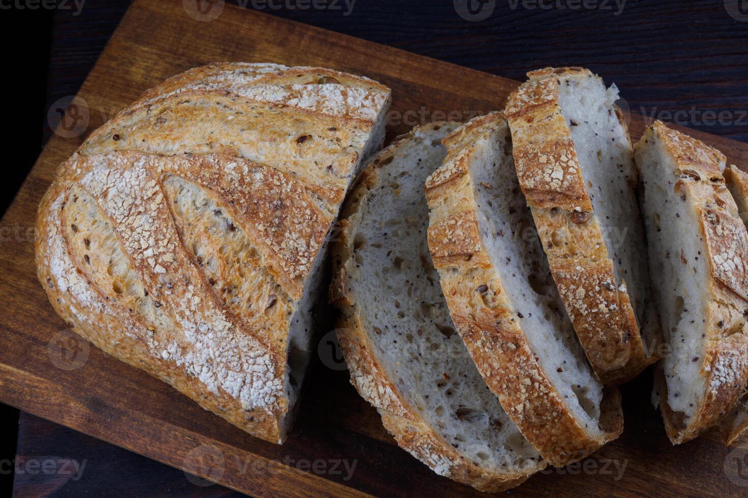 tagliare pagnotta con semi su un' di legno tavola. affettato pezzi di pane. arte pane. foto