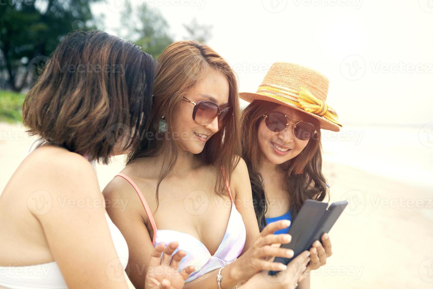 tre donne asiatiche che si rilassano sulla spiaggia estiva? foto