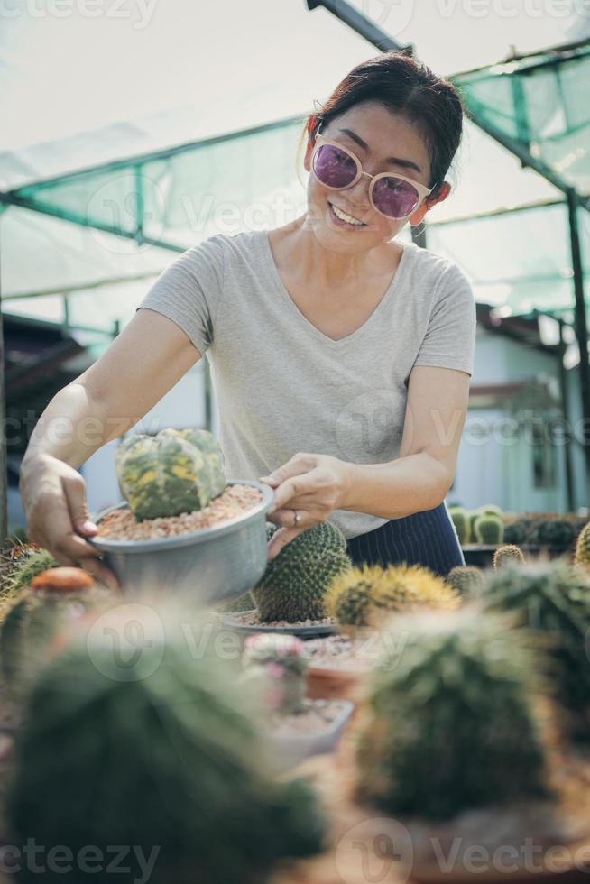 donna sorridente a trentadue denti che tiene in mano un vaso di cactus foto