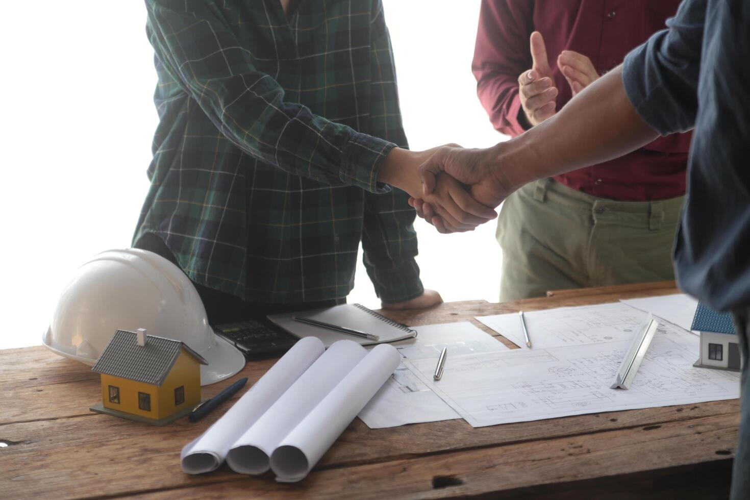 ingegnere e contraente aderire mani dopo firma contratto, loro siamo avendo un' moderno edificio progetto insieme. riuscito cooperazione squadra concetto foto