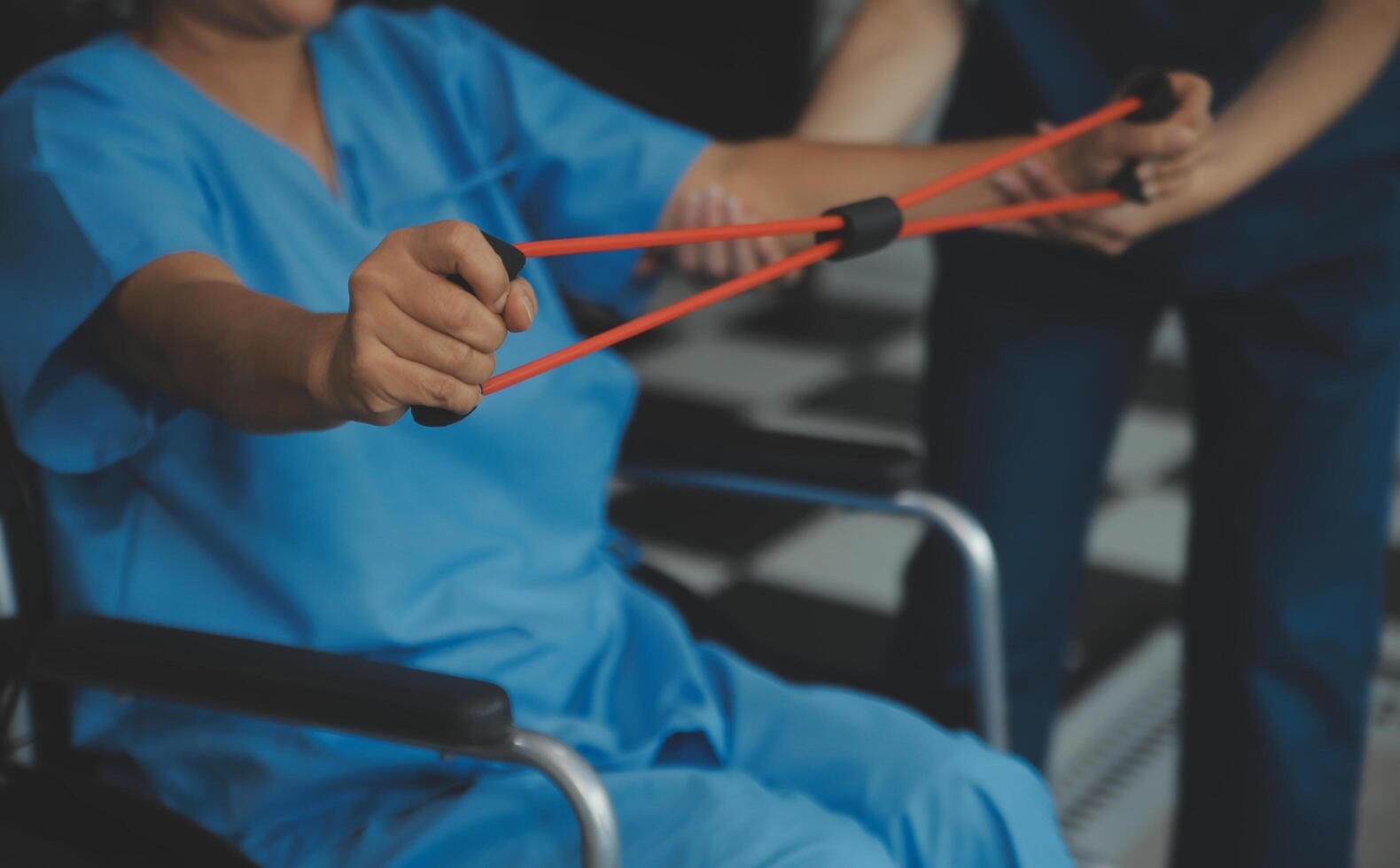 personale allenatore assistere anziano donna con resistenza gruppo musicale. reinserimento fisioterapia lavoratore porzione vecchio paziente a assistenza infermieristica casa. vecchio donna con allungare gruppo musicale essere allenato di fisioterapista. foto