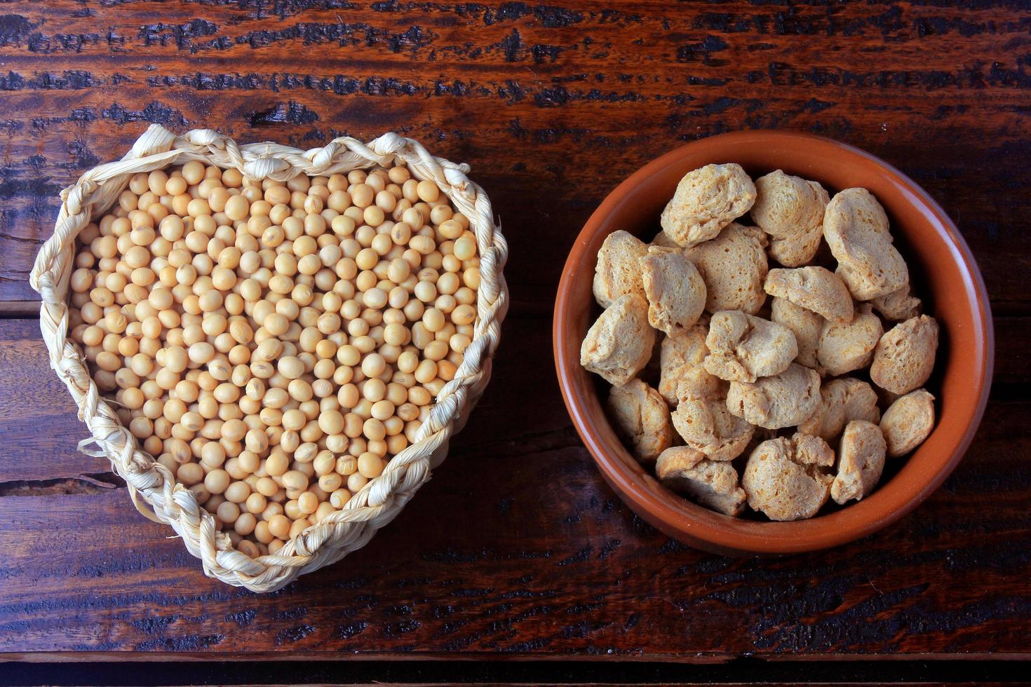 carne di soia, pezzi in una ciotola di ceramica marrone. pezzi di semi di soia crudi su fondo di legno rustico foto