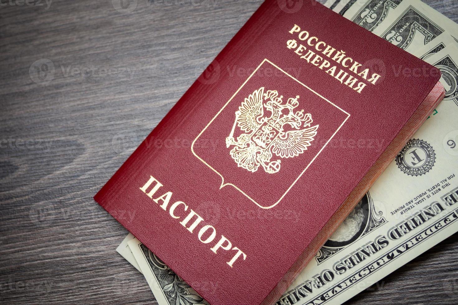 un passaporto straniero e dollari su uno sfondo di legno. foto