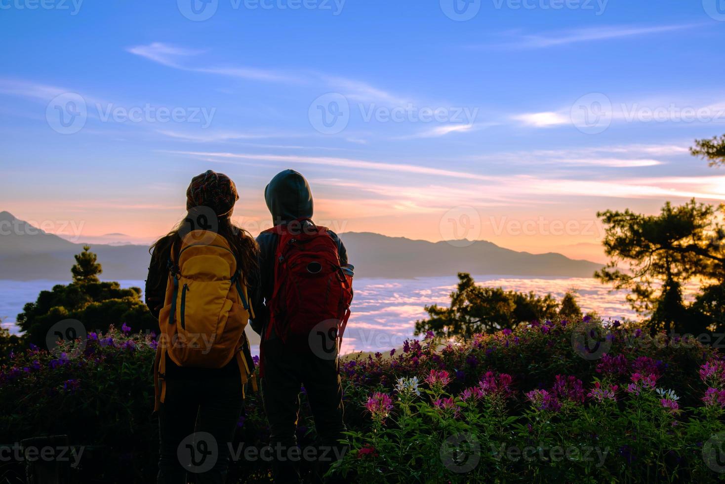 coppie asiatiche turisti con zaini in piedi a guardare la vista del paesaggio sulla montagna, bellissimo paesaggio e la luce del bel sole sul cielo foto