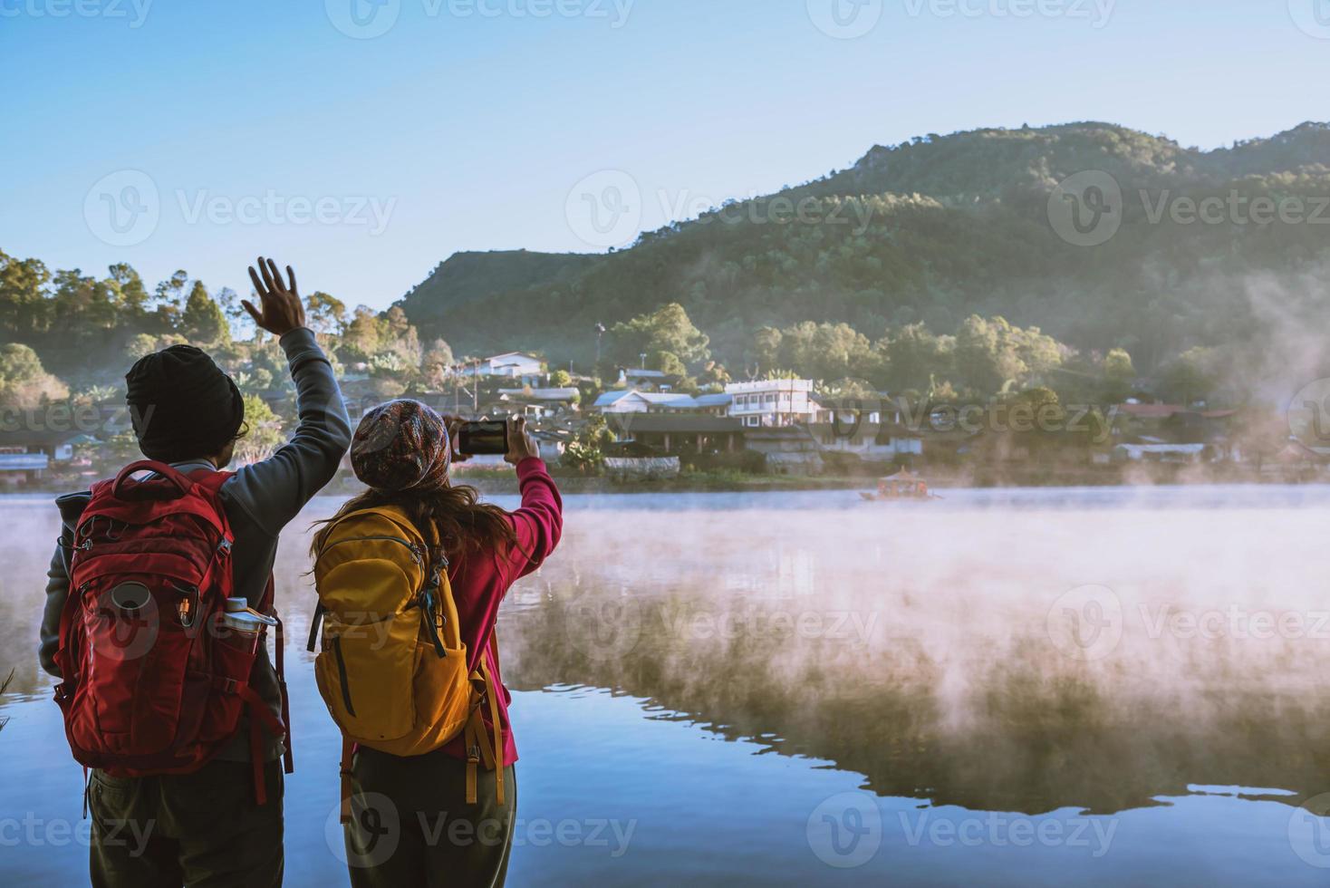 una coppia asiatica che sta in piedi e guarda la nebbia che si alza sul lago al mattino. viaggio ban rak thai village, mae hong son in thailandia. fai una foto al lago