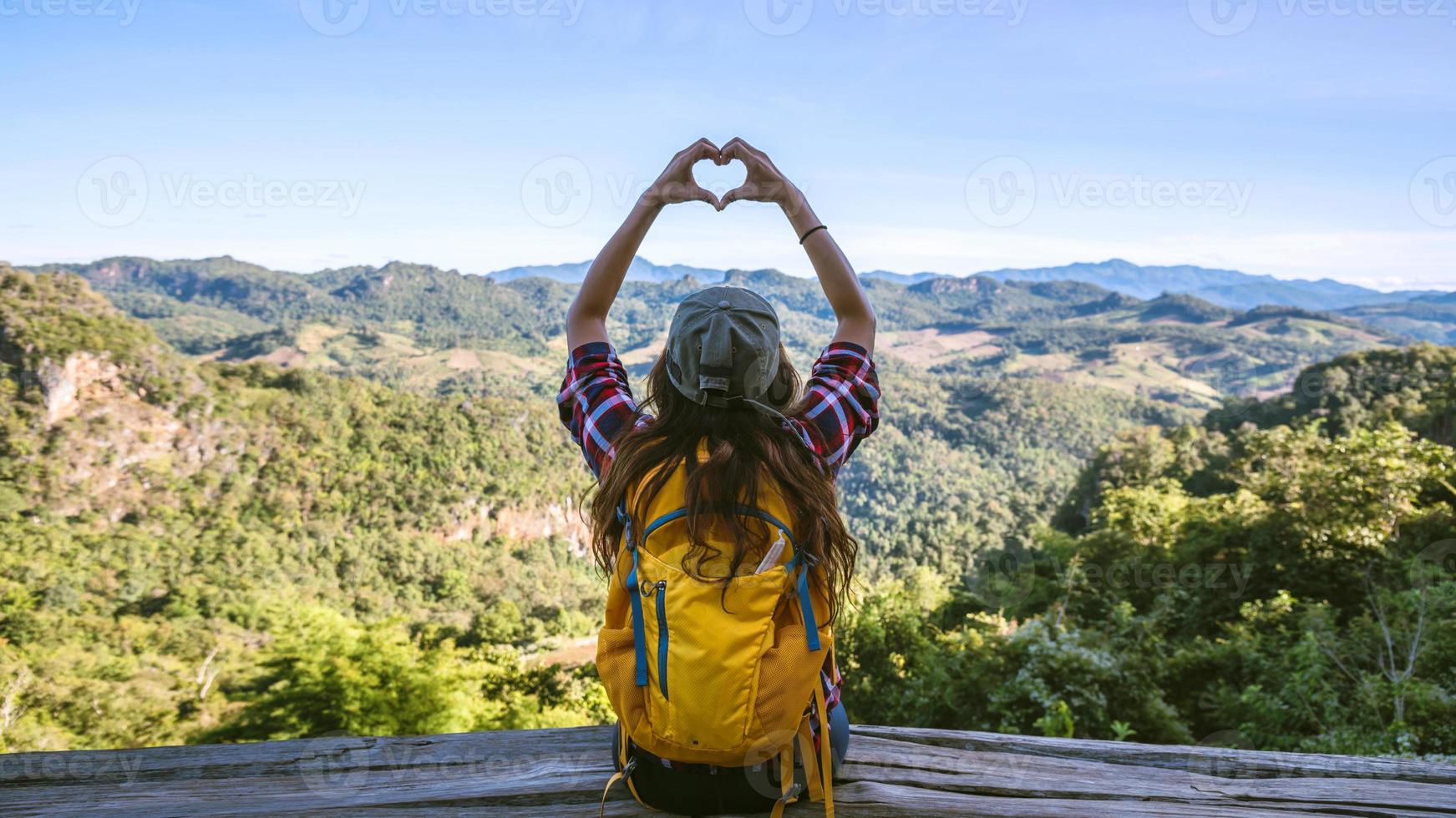 giovane turista con zaini felici di viaggiare ha alzato la mano per fare una forma a cuore e godersi lo scenario naturale sulla montagna. foto