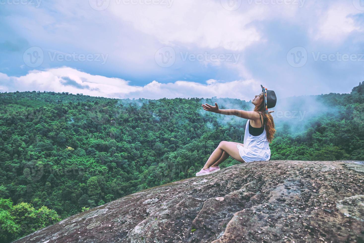 le donne asiatiche viaggiano rilassarsi durante le vacanze. sedersi su una scogliera rocciosa. legno di natura selvaggia sulla montagna. foto