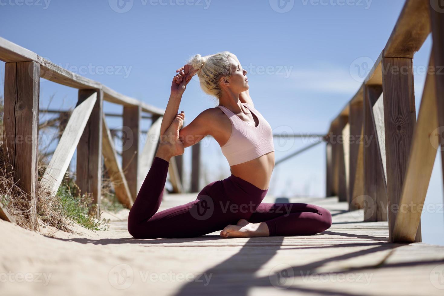 donna bionda caucasica che pratica yoga in spiaggia foto