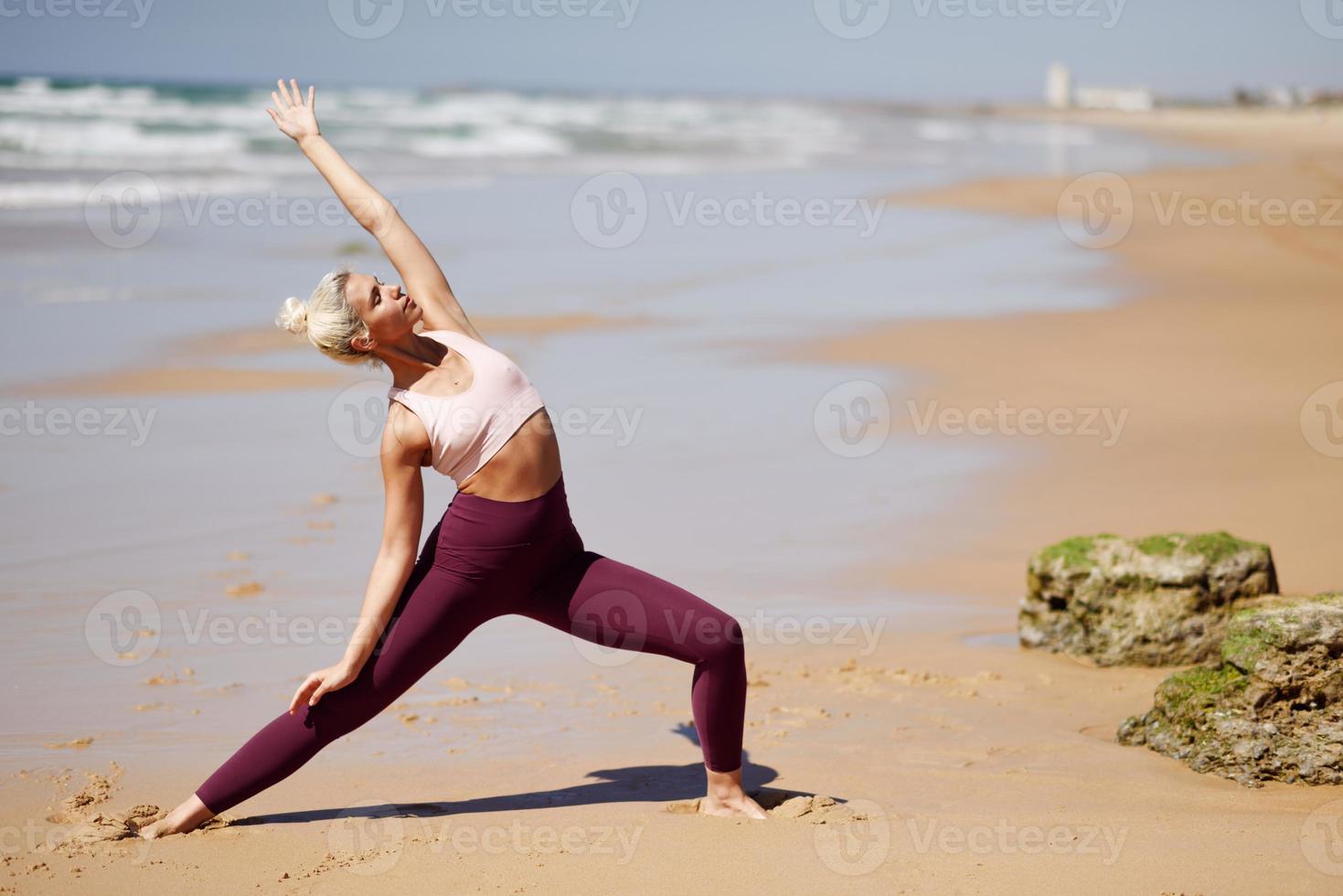 donna bionda caucasica che pratica yoga in spiaggia foto