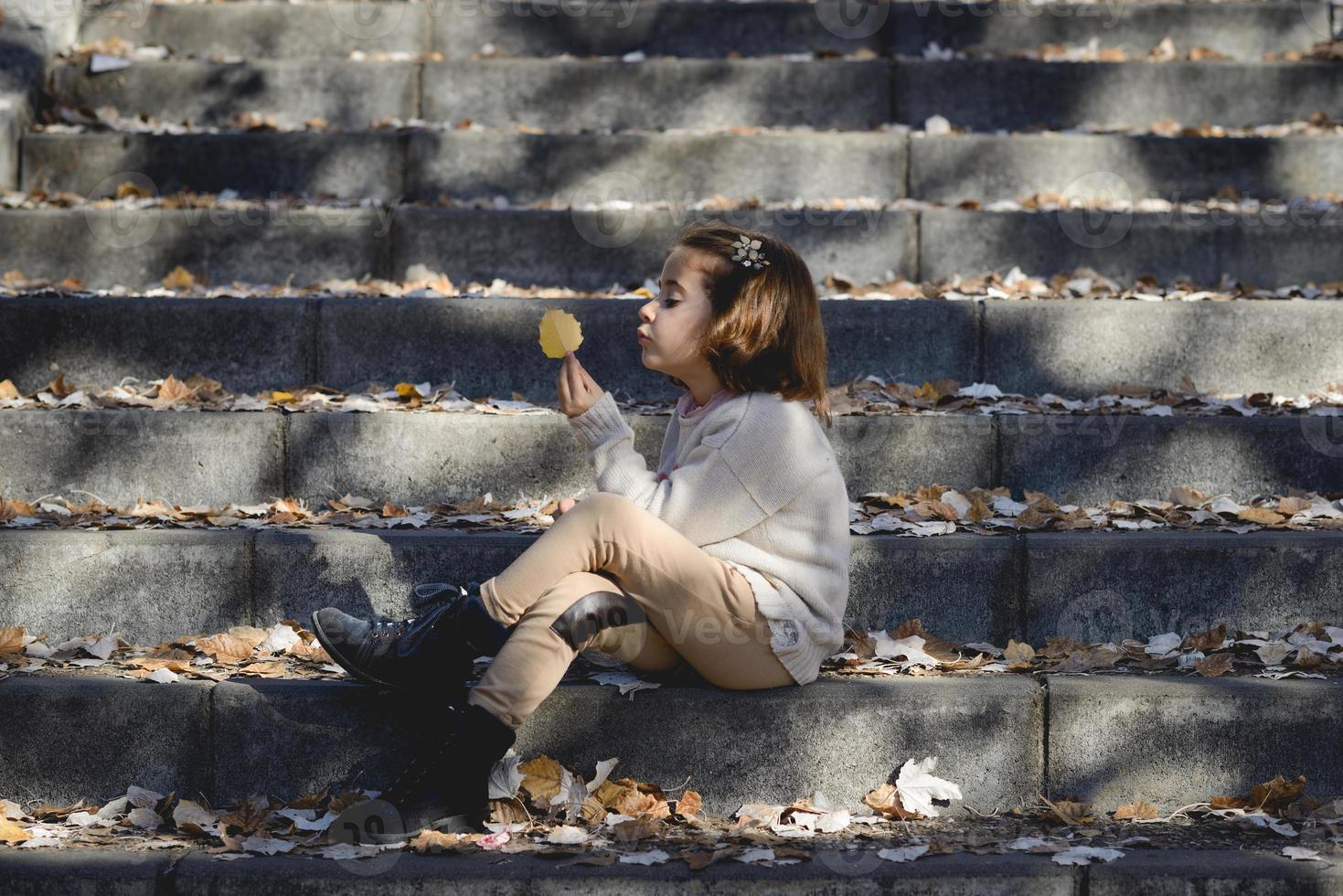 bambina che gioca in un parco cittadino in autunno foto