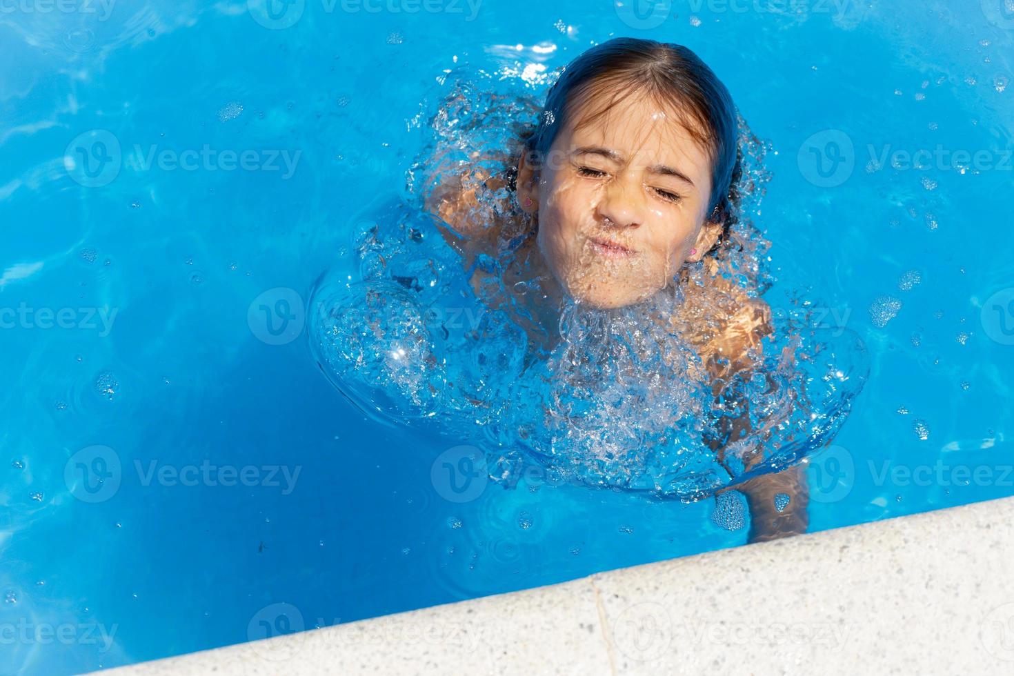 ragazza carina di otto anni che gioca in una piscina. foto