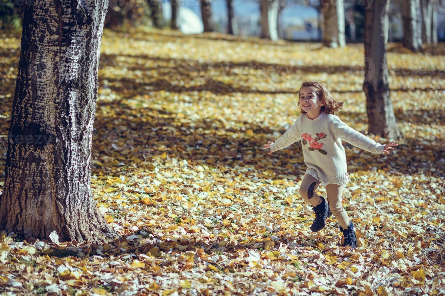 bambina che gioca in un parco cittadino in autunno foto