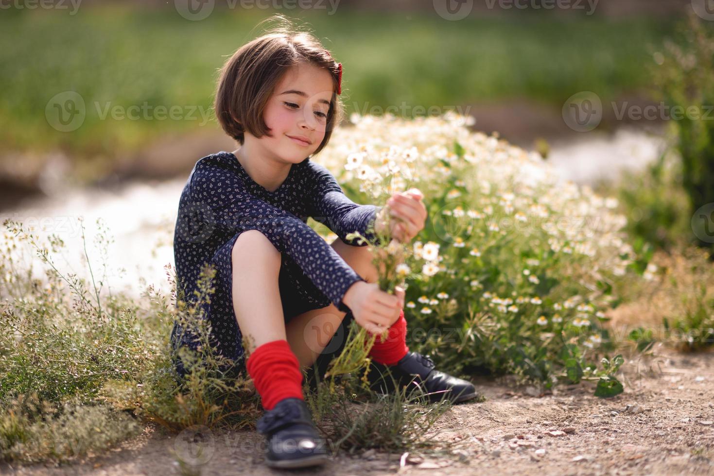 bambina seduta nel campo della natura che indossa un bel vestito foto