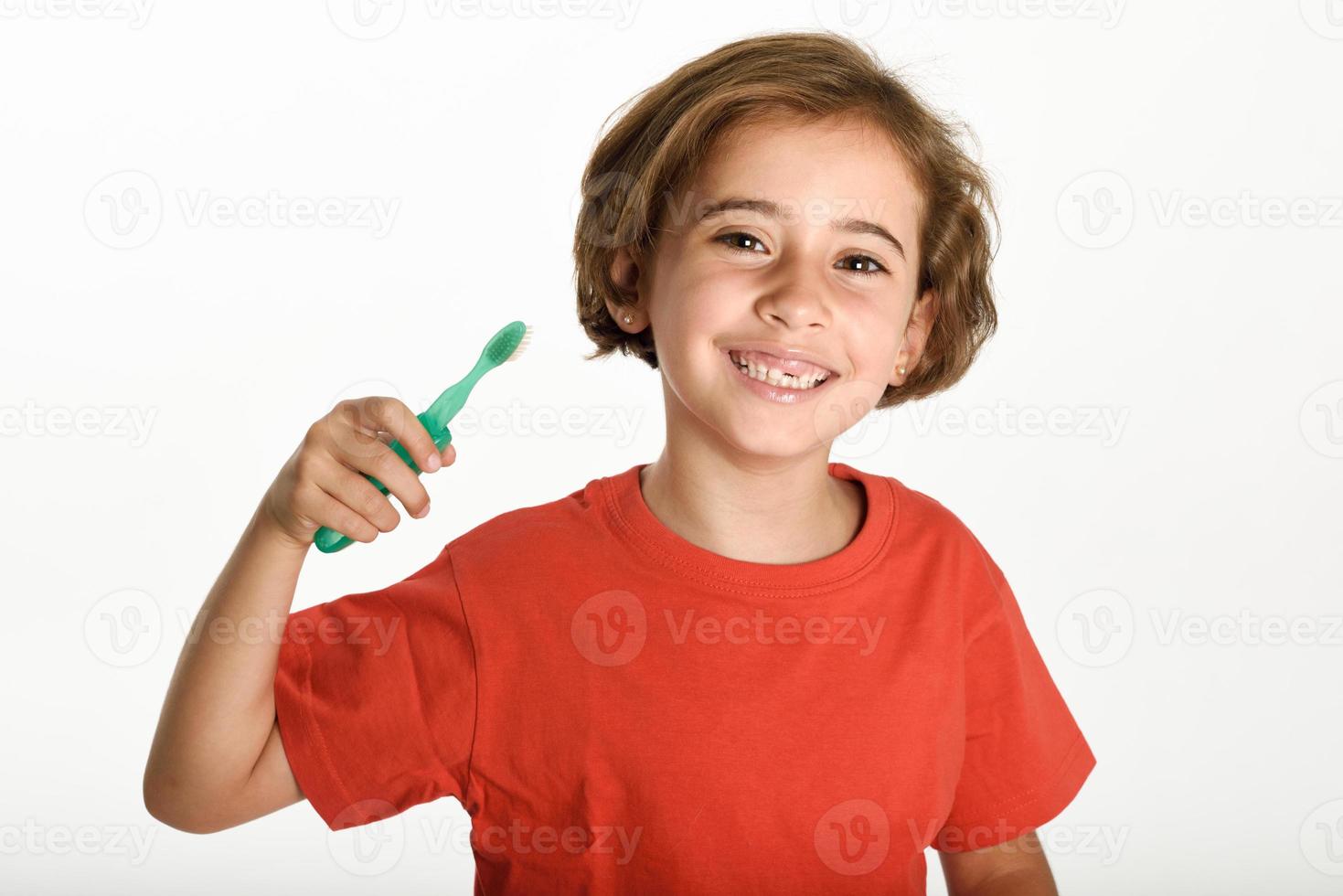 bambina felice che si lava i denti con uno spazzolino da denti foto