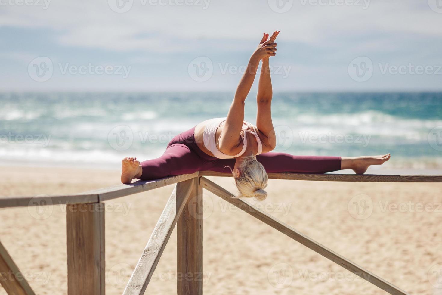 donna bionda caucasica che pratica yoga in spiaggia foto