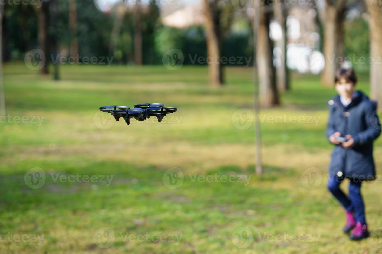 bambina di nove anni che manovra un drone giocattolo che vola con il telecomando foto