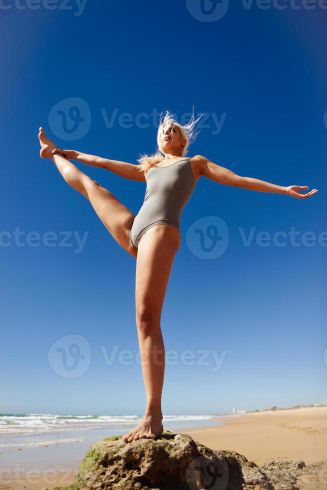 donna bionda caucasica che pratica yoga in spiaggia foto