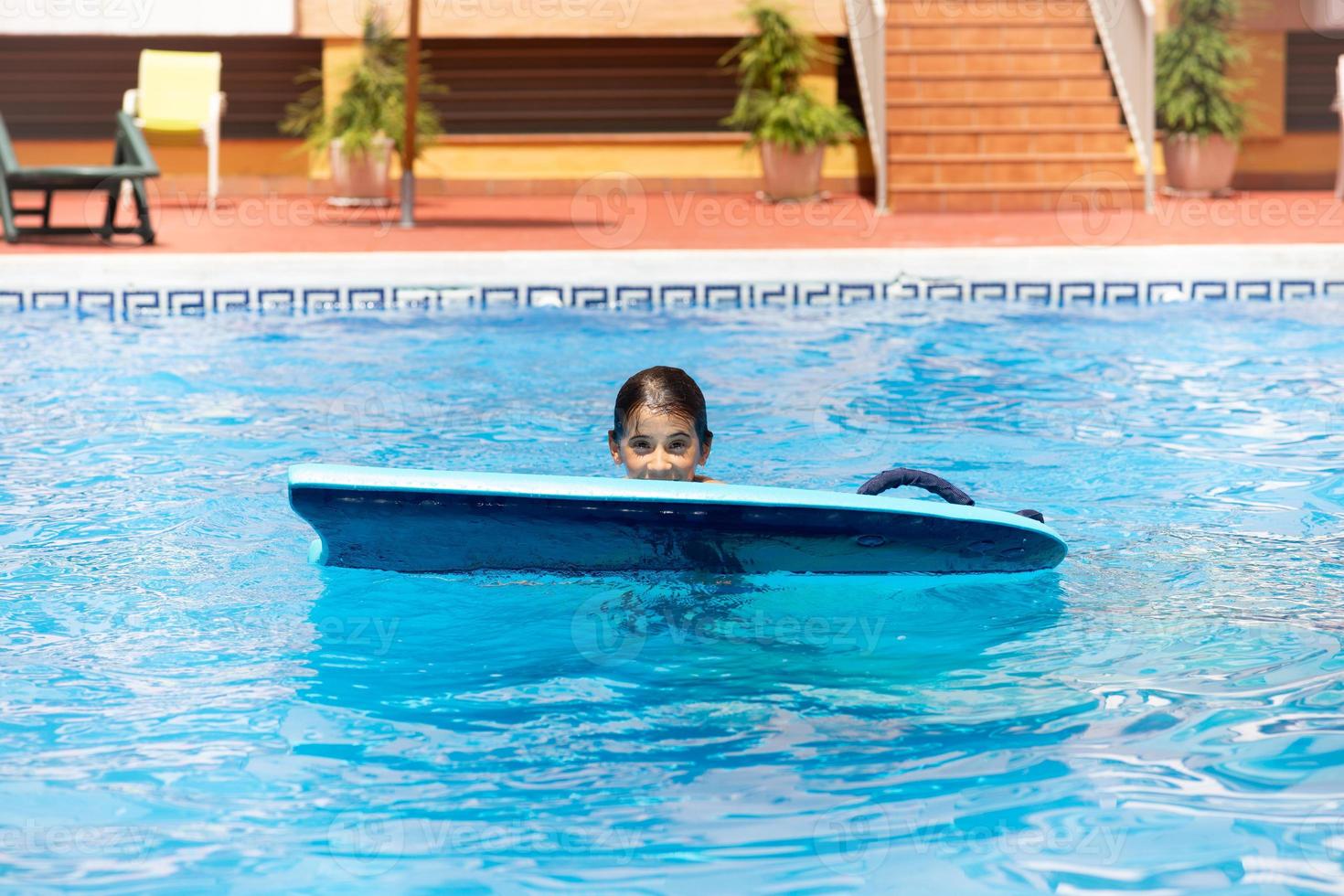 ragazza carina che gioca con un bodyboard in una piscina. foto