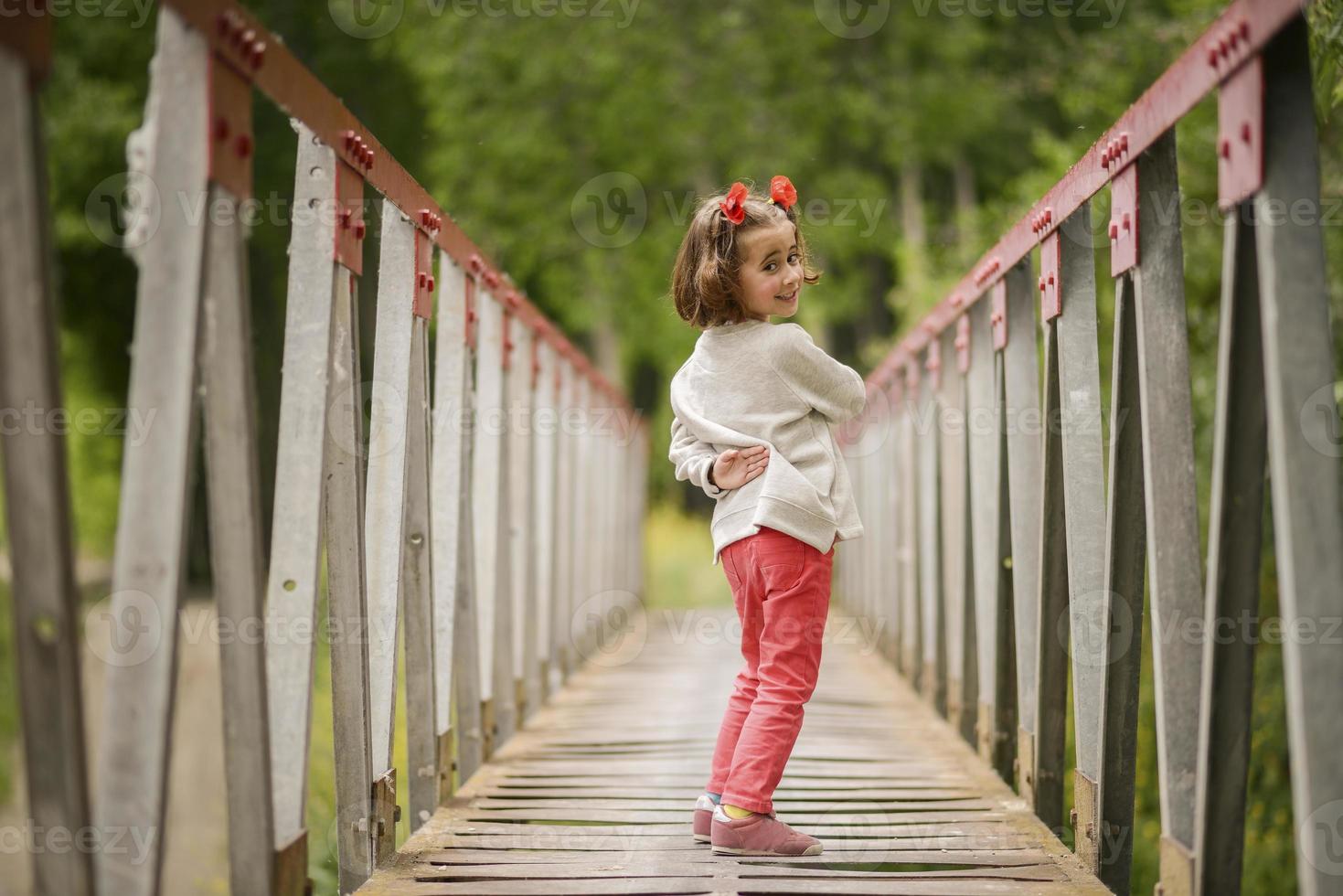 bambina carina che si diverte in un ponte rurale foto