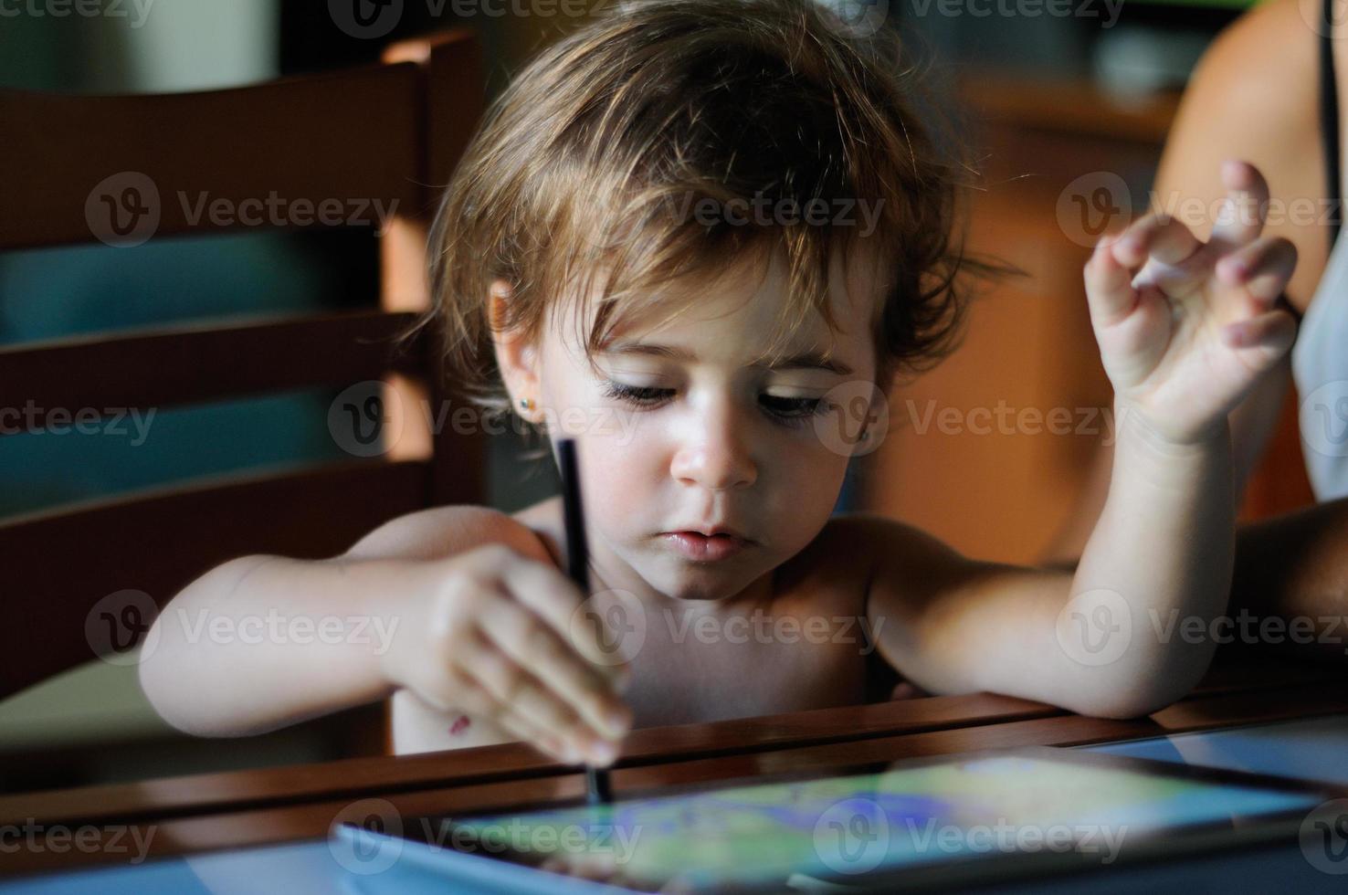 bambina che dipinge con una tavoletta digitale a casa. foto