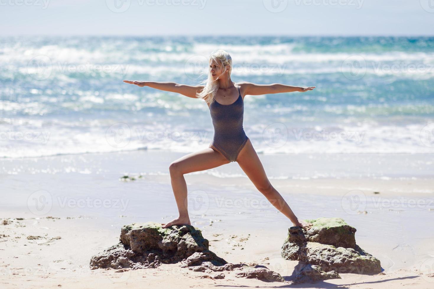 donna bionda caucasica che pratica yoga in spiaggia foto